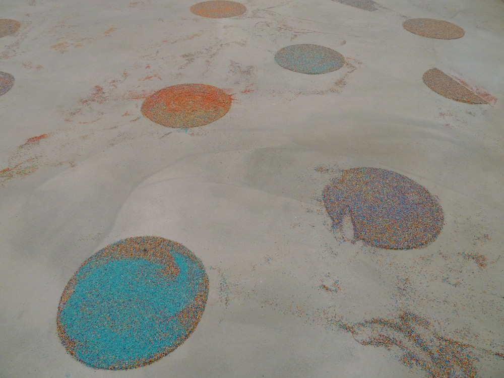 Art, artwork. An installation "Vacuumination" by Nika Span / Nika Špan. Material: A robot vacuum cleaner, coloured gravel. Exhibition: Homeland, MMKK, Klagenfurt, Austria